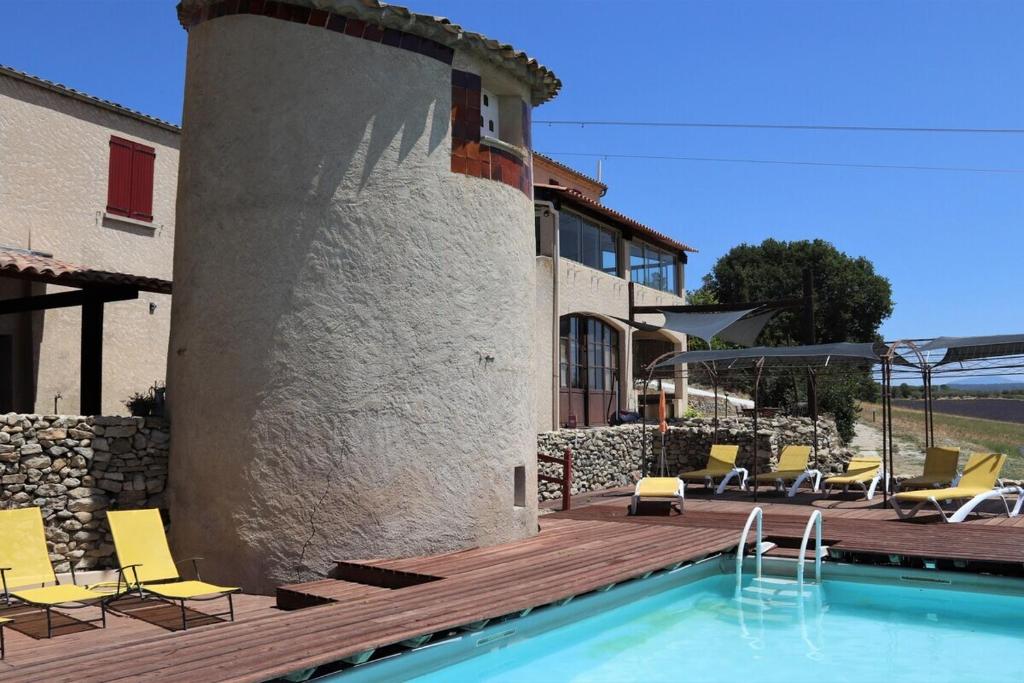 a house with a swimming pool and chairs and a building at La Petite Grande in Lurs