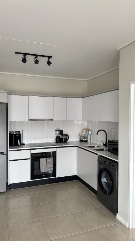 a kitchen with white cabinets and a washer at Elara in Sandton