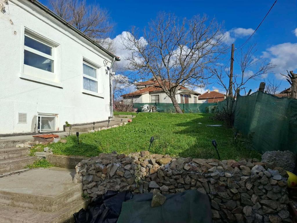a yard with a stone wall next to a white house at Millies Place in Elkhovo