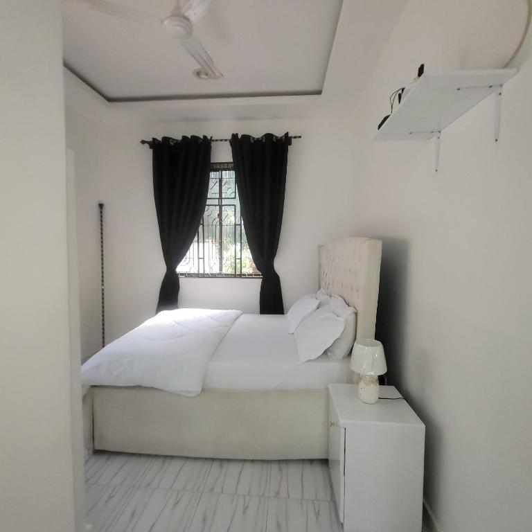 a white bedroom with a bed and a window at Mary homestays in Dar es Salaam
