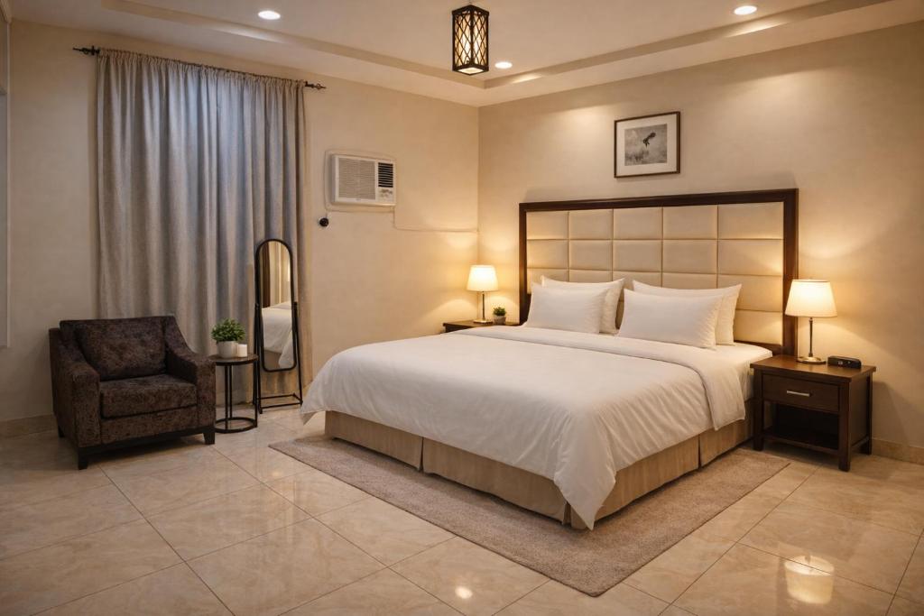 a bedroom with a large bed and a chair at Roaa Apartments شقق مخدومة in Al Qunfudhah