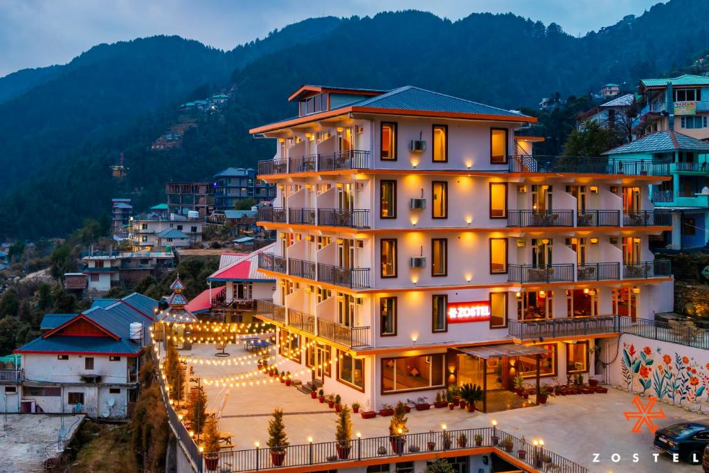 a large building with lights in front of a city at Zostel Dharamkot, Bhagsu in McLeod Ganj