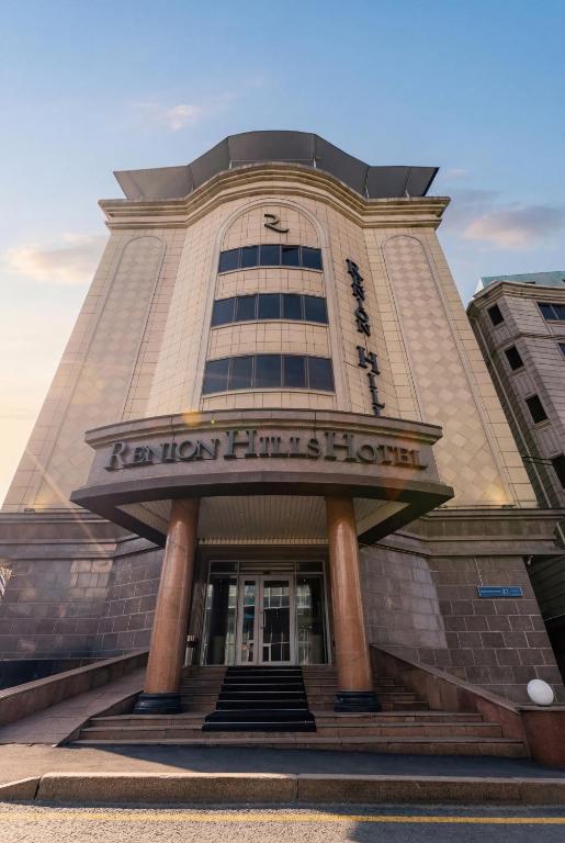 a building with a sign on the front of it at Renion Hills Hotel in Almaty