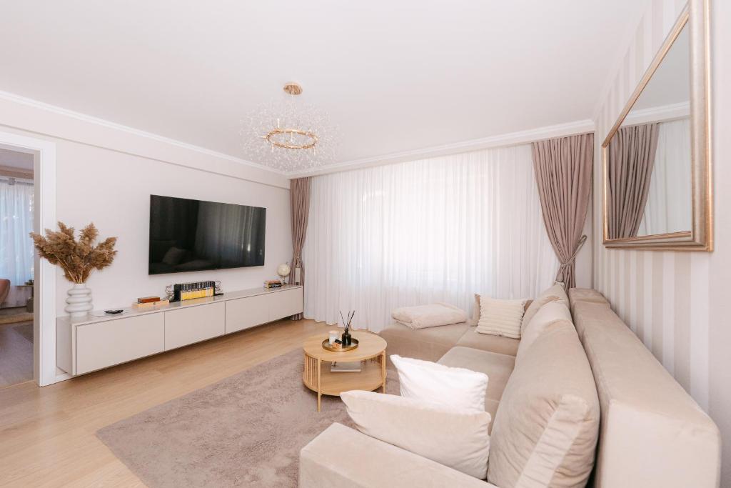 a white living room with a couch and a tv at Sovata Apartment in Sovata