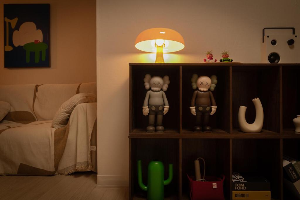 a book shelf with two figurines on it next to a couch at 퍼즈스테이 Pause Stay in Chuncheon