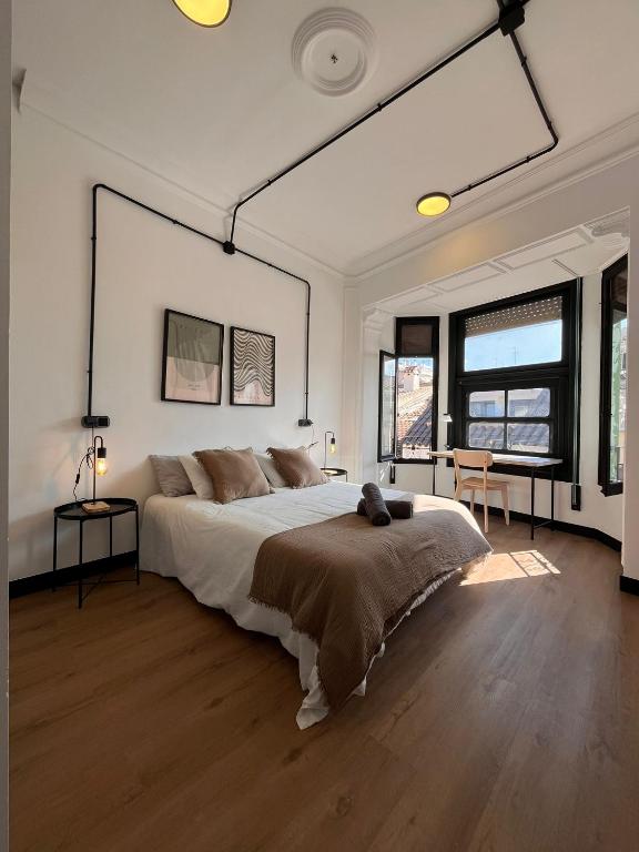 a white bedroom with a large bed and two windows at Terrazas de la Catedral III in Castellón de la Plana