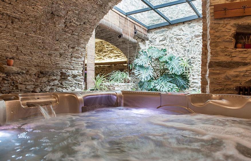 a large hot tub in a stone building with a window at Can Baldiret, El Port de la Selva in La Vall de Santa Creu