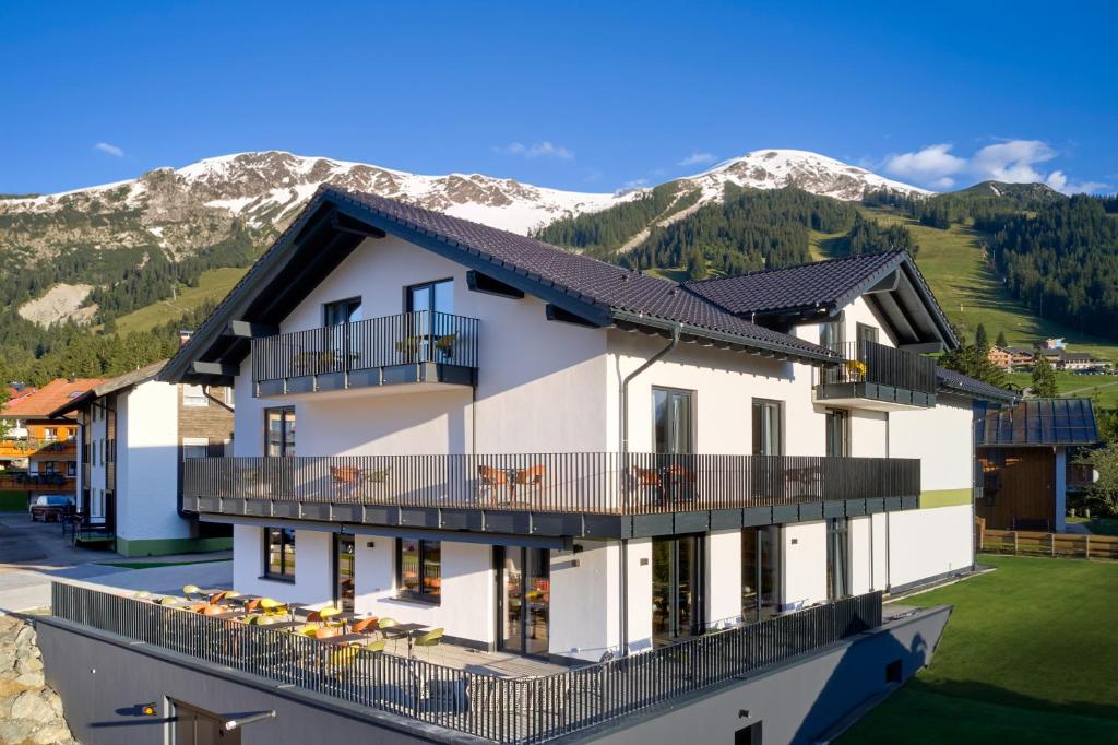 a building with a balcony and mountains in the background at BergBuddies Oberjoch in Bad Hindelang