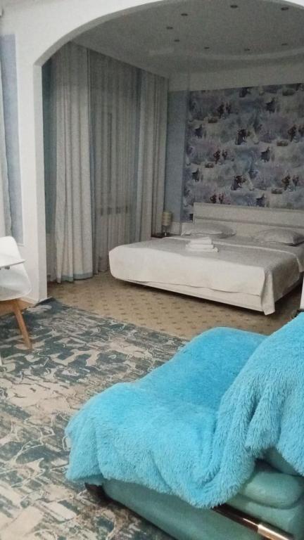 a bedroom with a large bed with a blue blanket at Delight Сая in Astana