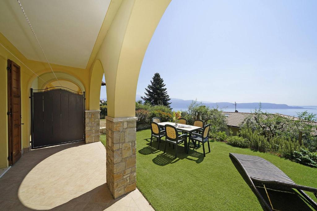 a patio with a table and chairs on the grass at Villetta Enzo - Gardagate in Toscolano Maderno