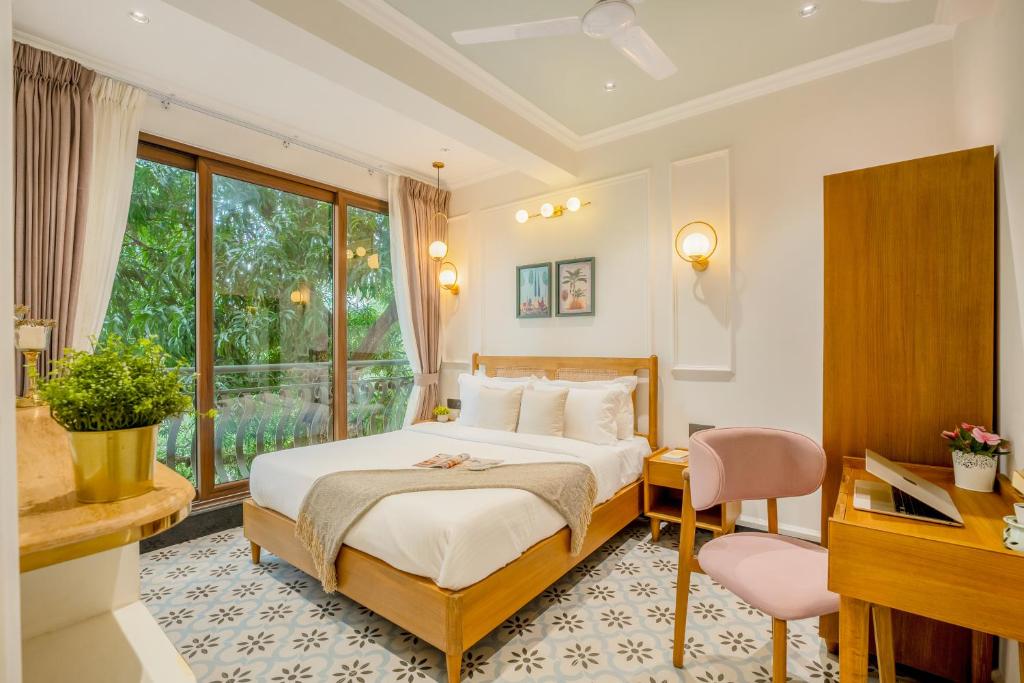 a bedroom with a bed and a desk and a window at Staymaster Veridian Standard 2BHK Near Calangute Beach in Calangute