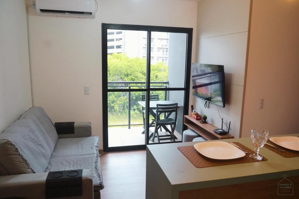 a living room with a couch and a table and a television at Refugio Premium 2 Quartos 1 Suite WiFi Ar e Garagem in Pelotas
