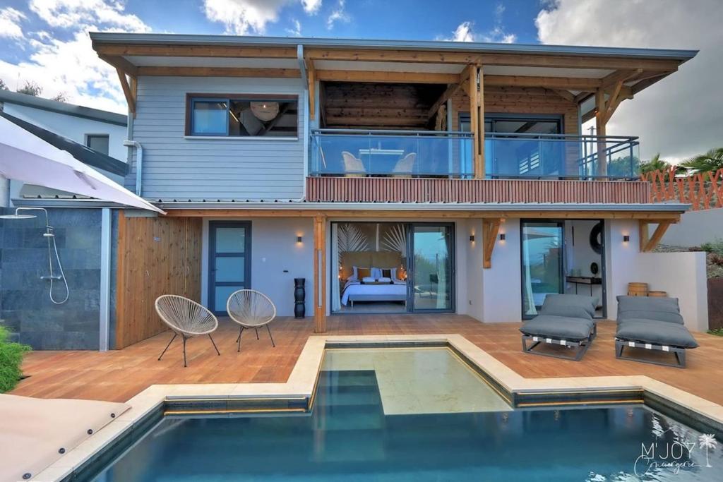 a home with a pool and a house with a deck at Villa Austral et Lagons in Étang-Salé