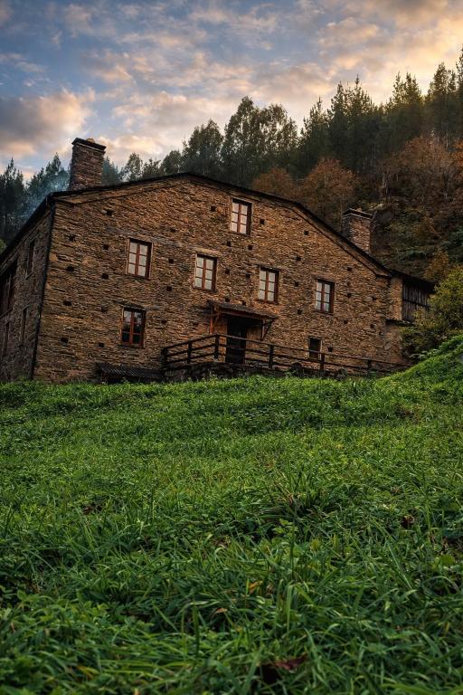 an old brick building on a grassy hill at Casa do Fidalgo in A Pontenova