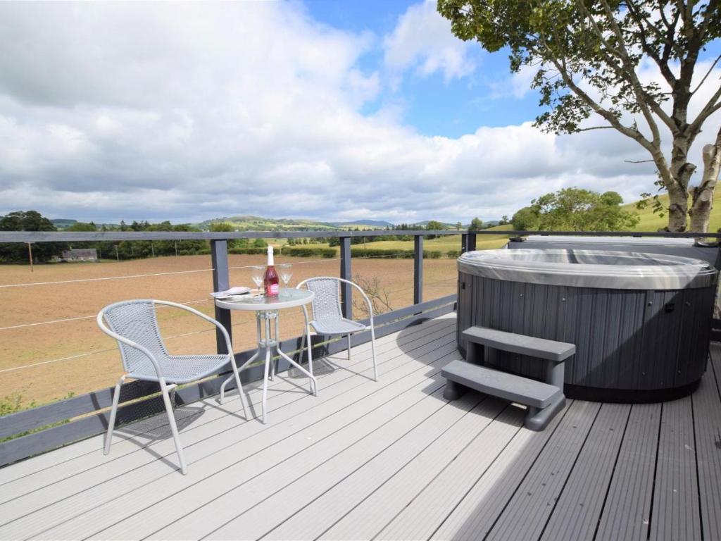 a deck with a hot tub and a table and chairs at 1 Bed in Biggar oc-82923 in Biggar