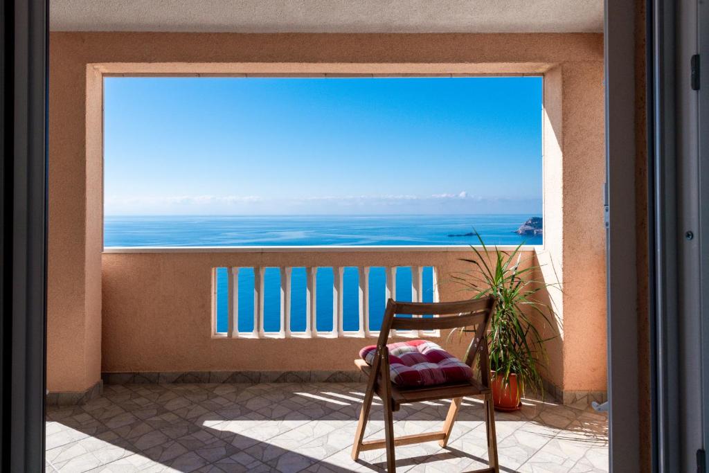 a chair on a balcony with a view of the ocean at Apartments Mrkan 2 in Cavtat