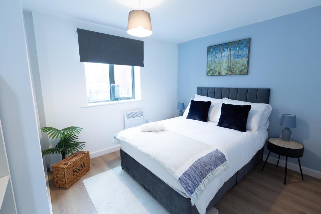 a bedroom with a large bed with blue walls at Spacious City Centre Apartment with Balcony in Wolverhampton