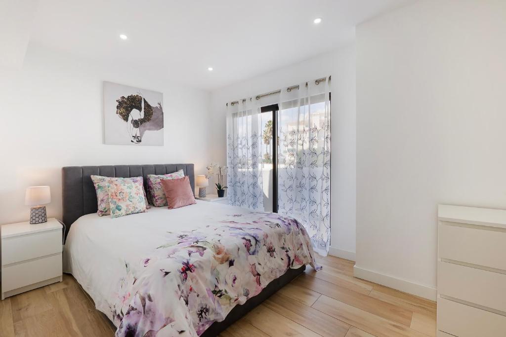 a white bedroom with a bed and a window at Central Condo-Pool with AC and garden by Algarve Dream Holidays in Albufeira