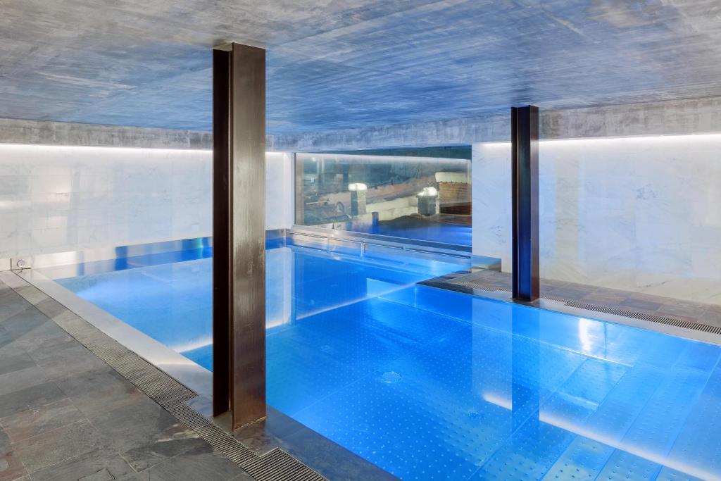 a large swimming pool with blue water in a building at Aux Pieds du Roi - Suite & Spa in Breuil-Cervinia