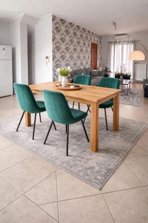 a wooden table and green chairs in a living room at ΗΣΥΧΟ ΚΑΙ ΑΝΕΤΟ ΔΙΑΜΈΡΙΣΜΑ in Lamía