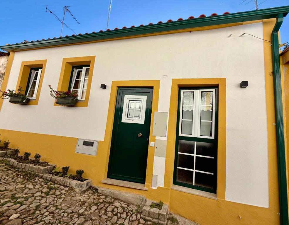 a house with a green door and windows at Casa das Flores in Sardoal