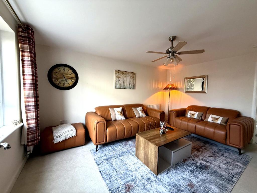 a living room with two leather couches and a table at Loch Ness Hideaway in Inverness
