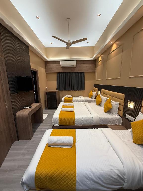 a hotel room with three beds with yellow accents at Hotel Sweet Inn in Mumbai