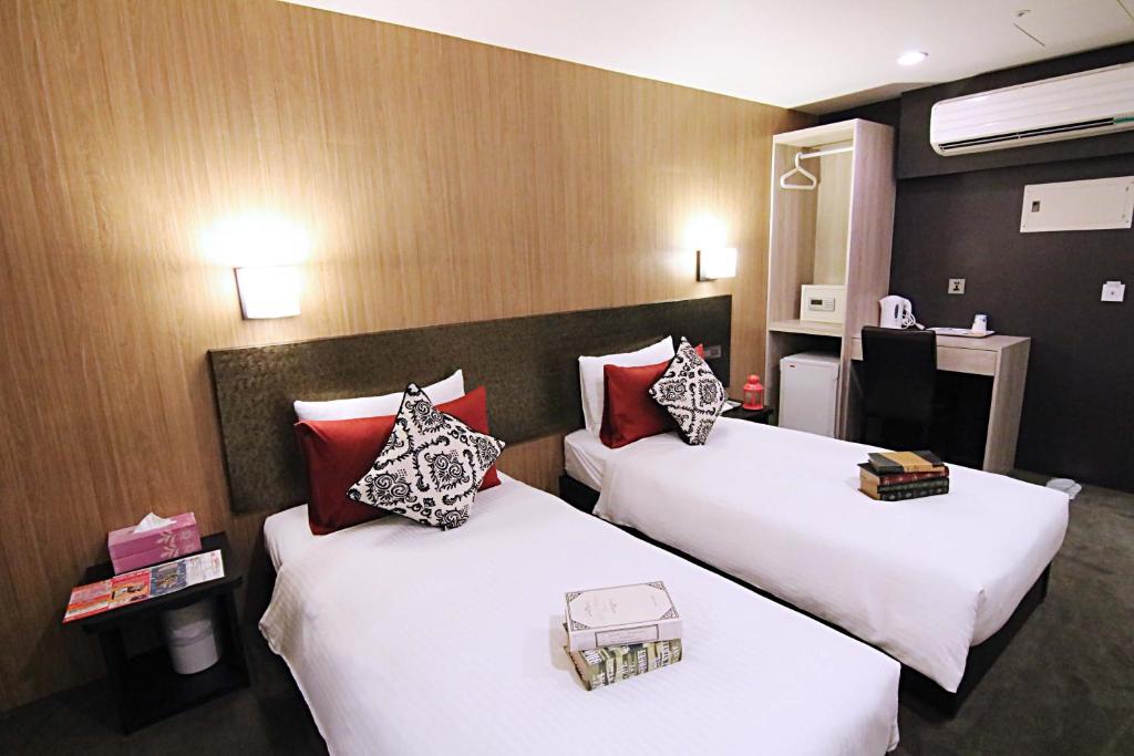 two beds in a hotel room with white and red pillows at Hotel 6 - Wannien in Taipei