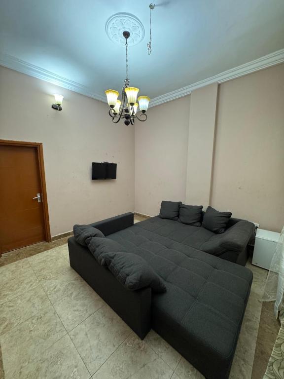 a living room with a bed and a chandelier at Jassehs Apartments in Brusubi