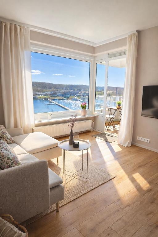 a living room with a couch and a large window at Strandhafer-Balkon mit Meerblick- 2 Min zum Strand in Schausende