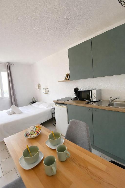 a room with a table and a bed and a kitchen at Studio - Plage de Calais - Skatebeach in Calais