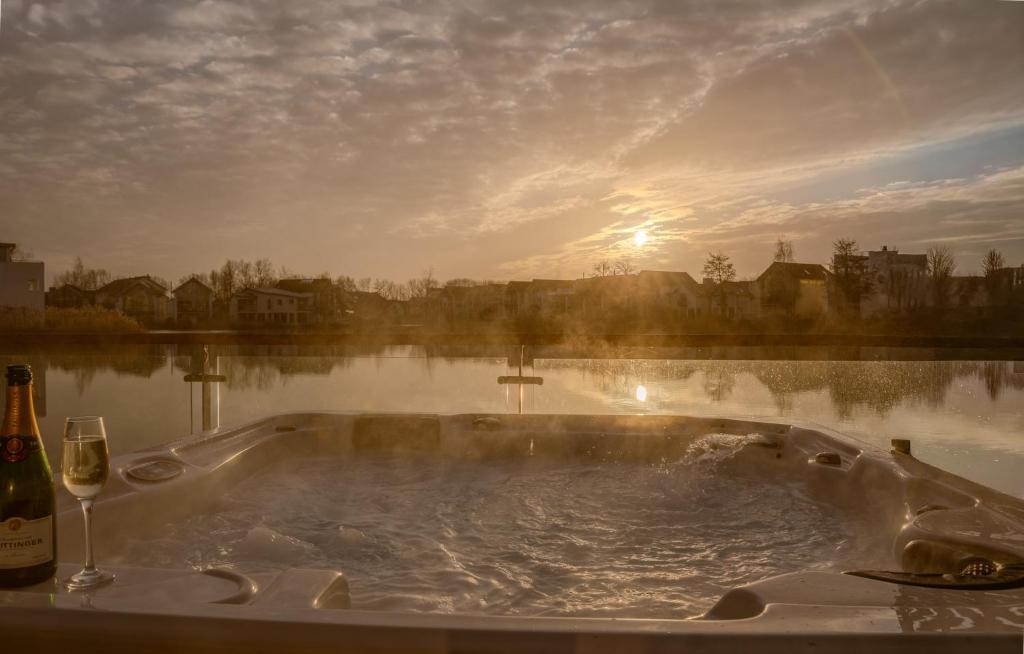 a bath tub sitting next to a body of water at Lakeside Cotswolds Retreat with Private Hot Tub set on Lower Mill Estate in Somerford Keynes
