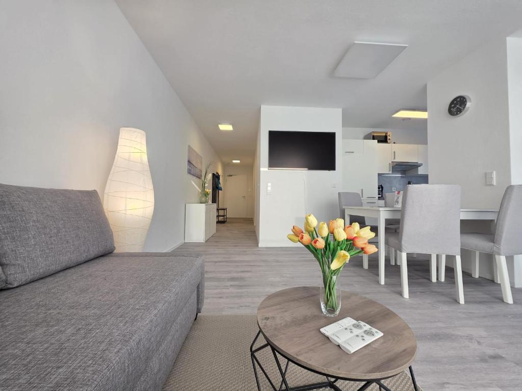 a living room with a couch and a table with flowers at Ferienwohnung NordTroll in Norden