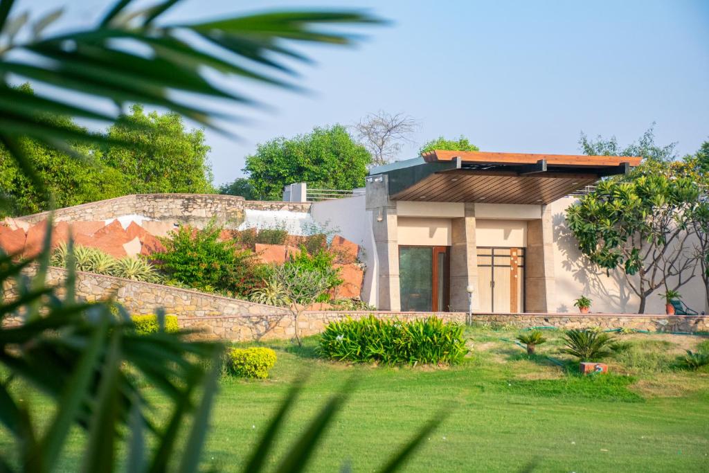 a house with a stone wall and a yard at Shlaka Farms in Jaipur