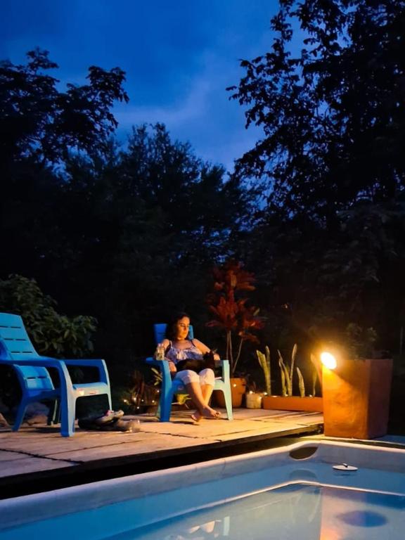 a woman sitting in a chair next to a swimming pool at El Cielo Biohospedaje - Reserva Natural Sostenible in Tena