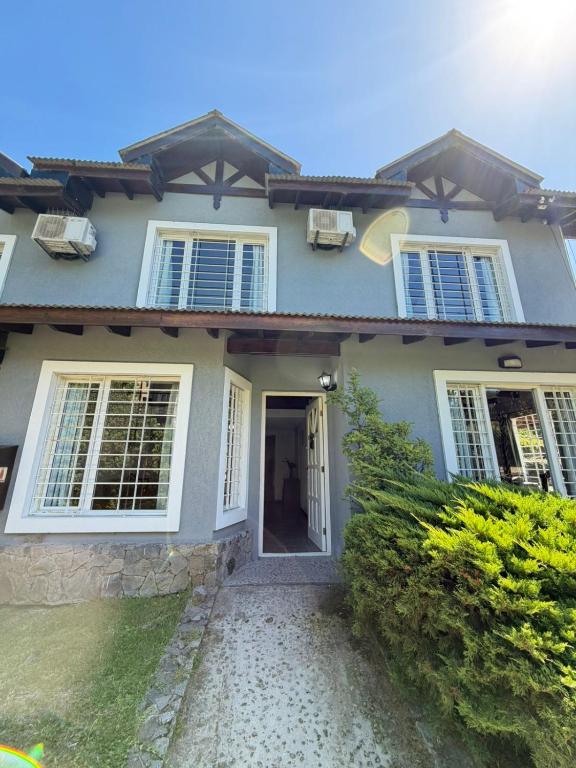 a house with a white door and windows at VALERIA 4 Ambientes in Valeria del Mar