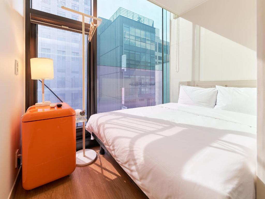 a bedroom with a bed and a large window at K9 Myeongdong Hotel in Seoul