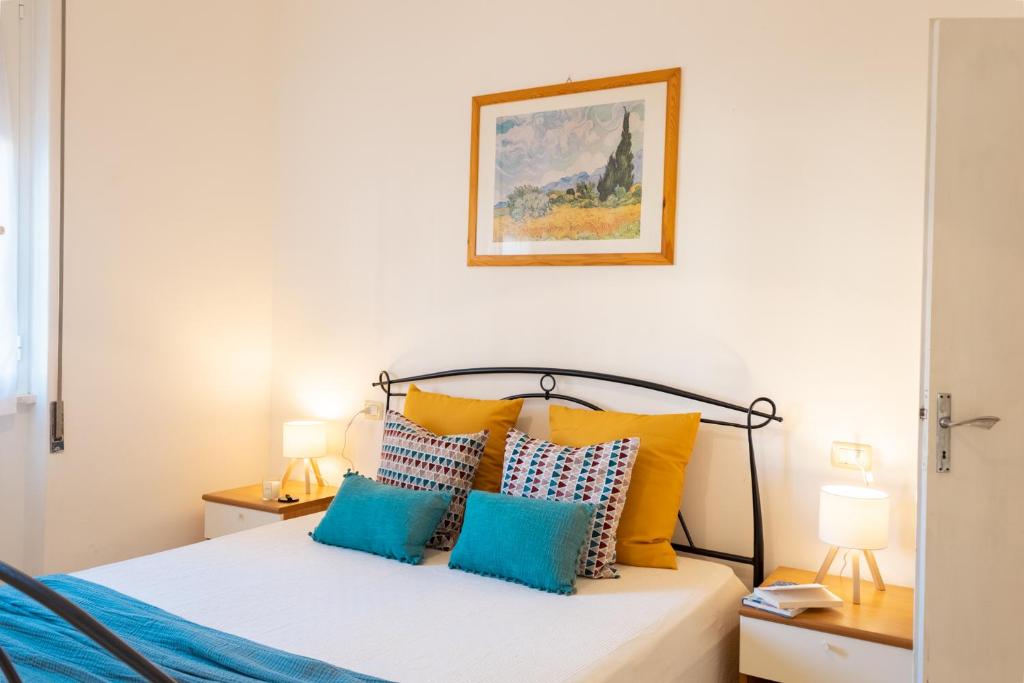 a bedroom with a bed with yellow and blue pillows at Follonica Vacanze 7 in Follonica