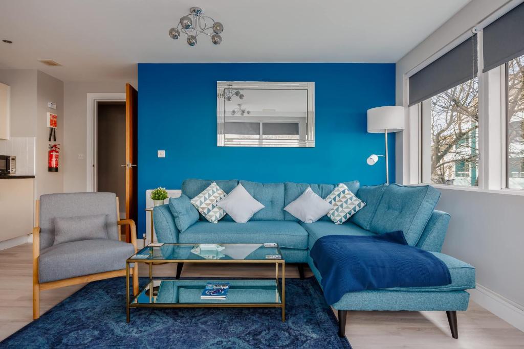 a blue living room with a blue couch and a chair at Seafarers - Contemporary Apartment, Central Location in Poole