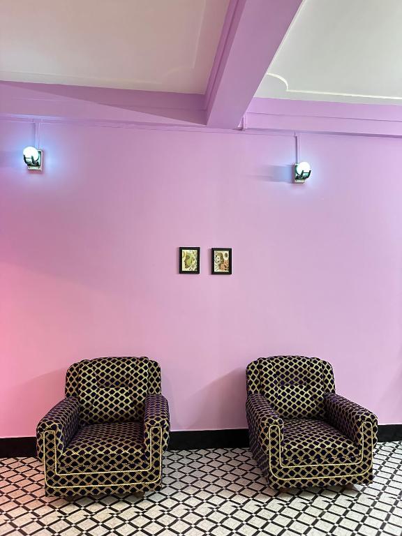 two chairs in a room with a pink wall at Zen Garden Homestay in Jorhat