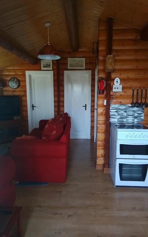 a living room with a red couch and a stove at Hamishs log cabin in Blaenau-Ffestiniog
