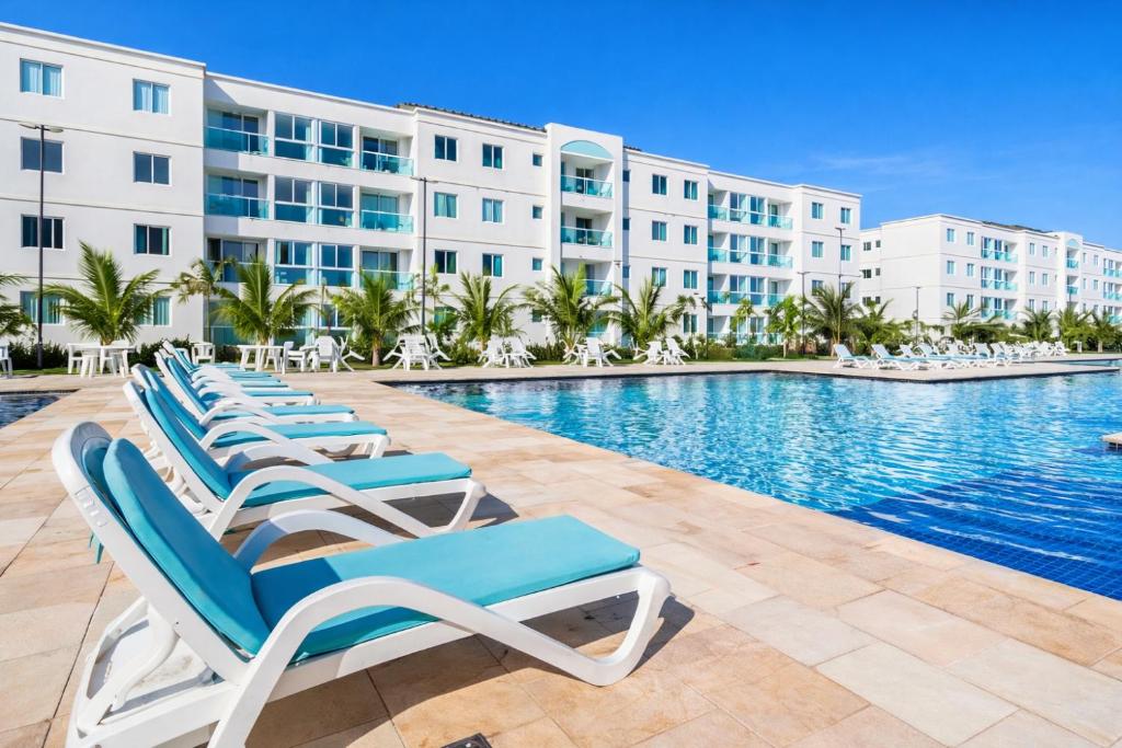 a row of lounge chairs next to a swimming pool at a resort at Apto Porto de Galinhas in Porto De Galinhas