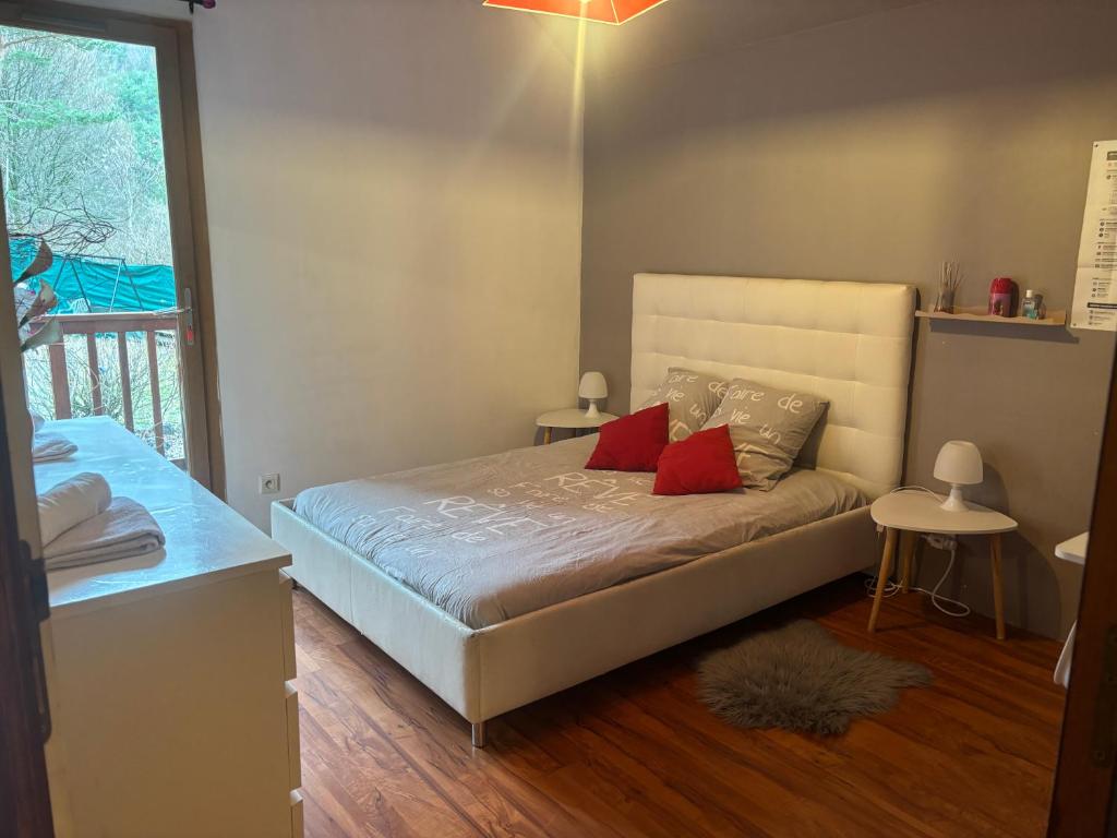 a bedroom with a bed with two red pillows at Chambre Serres Ponçon in Savines