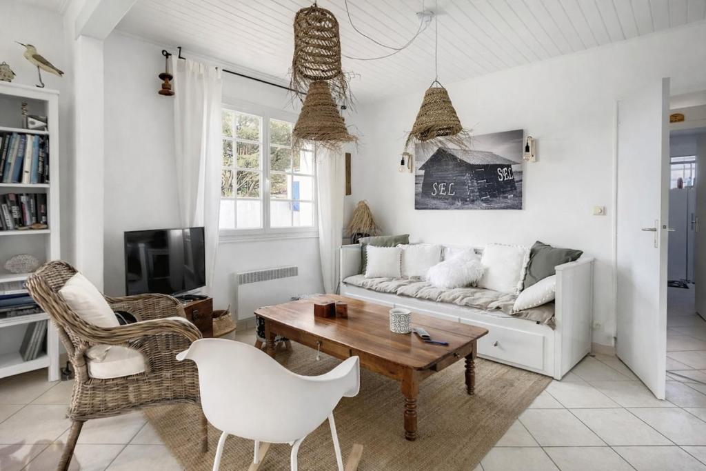 a living room with a couch and a table and chairs at L'écrin des Ormeaux - sur l'île - 300 m de la plage in Barbâtre