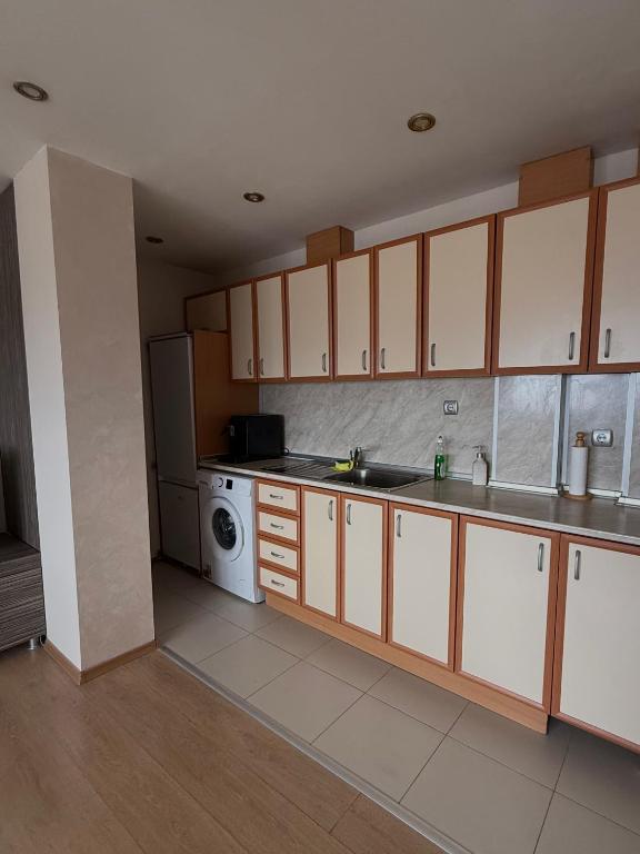 a kitchen with white cabinets and a washing machine at Apartment Rozen in Varna City
