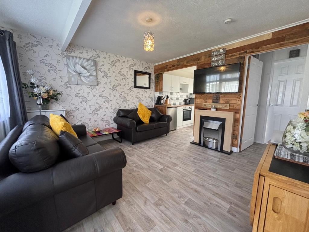 a living room with a couch and a fireplace at 121 Sunbeach - Two bed Chalet at Scratby - Sleeps 5, pet friendly - plus WiFi, bed linen and towels included - FREE swimming passes and Entertainment - Only 300m from the beach in Scratby