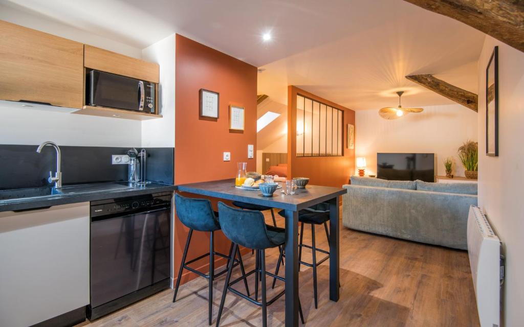 a kitchen with a table and a living room at La Nef - Climatisation, Parking & Wifi à 150m de la Cathédrale in Rodez