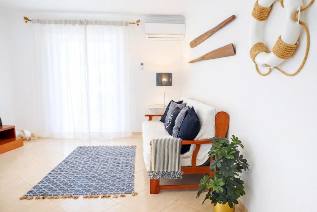 a living room with a couch and a blue rug at Avenue Apartment - Family-friendly T2 - Estacionamento Privado in Quarteira