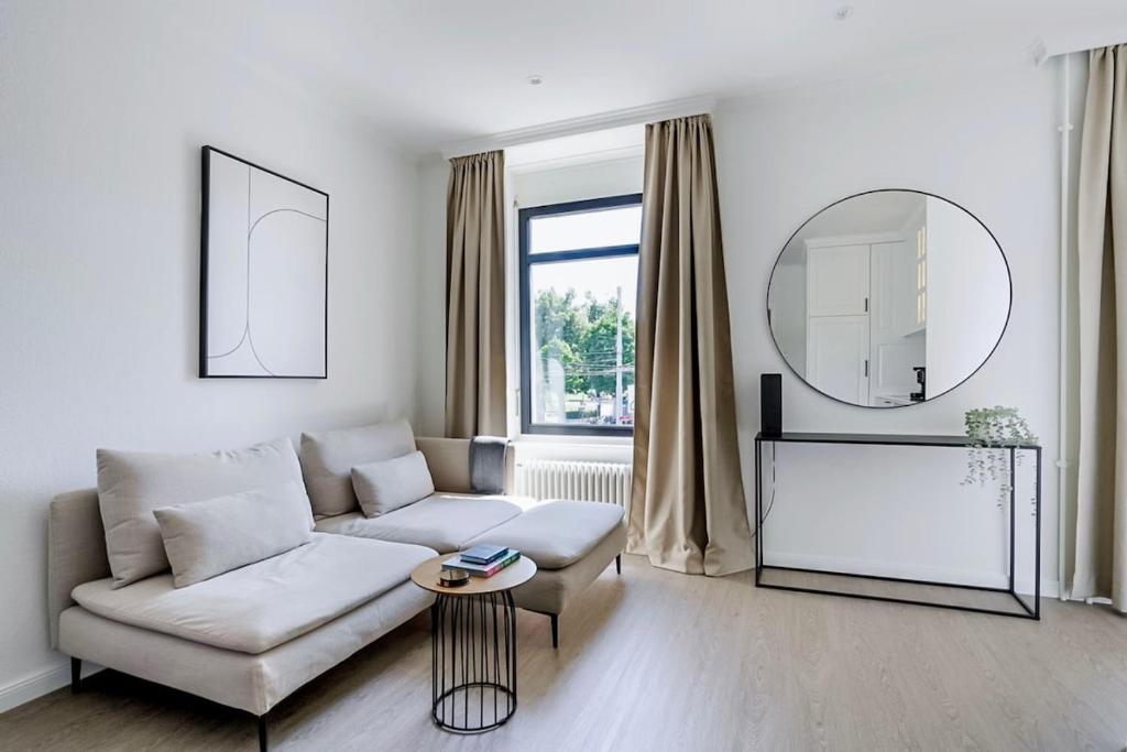 a living room with a white couch and a mirror at Oak Suite · District 4 in Zurich