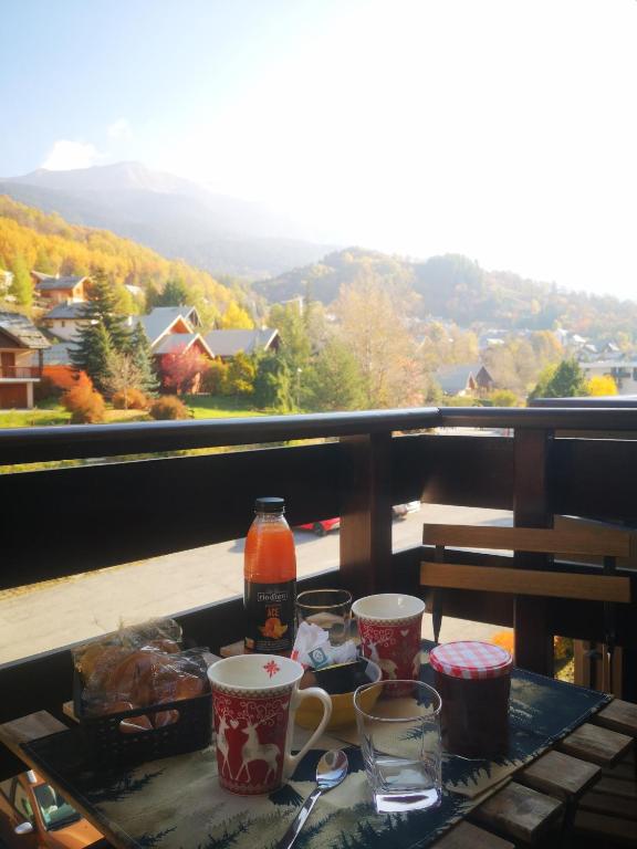 a table with cups on a balcony with a view at Cosy studio in Serre Chevalier in Saint-Chaffrey